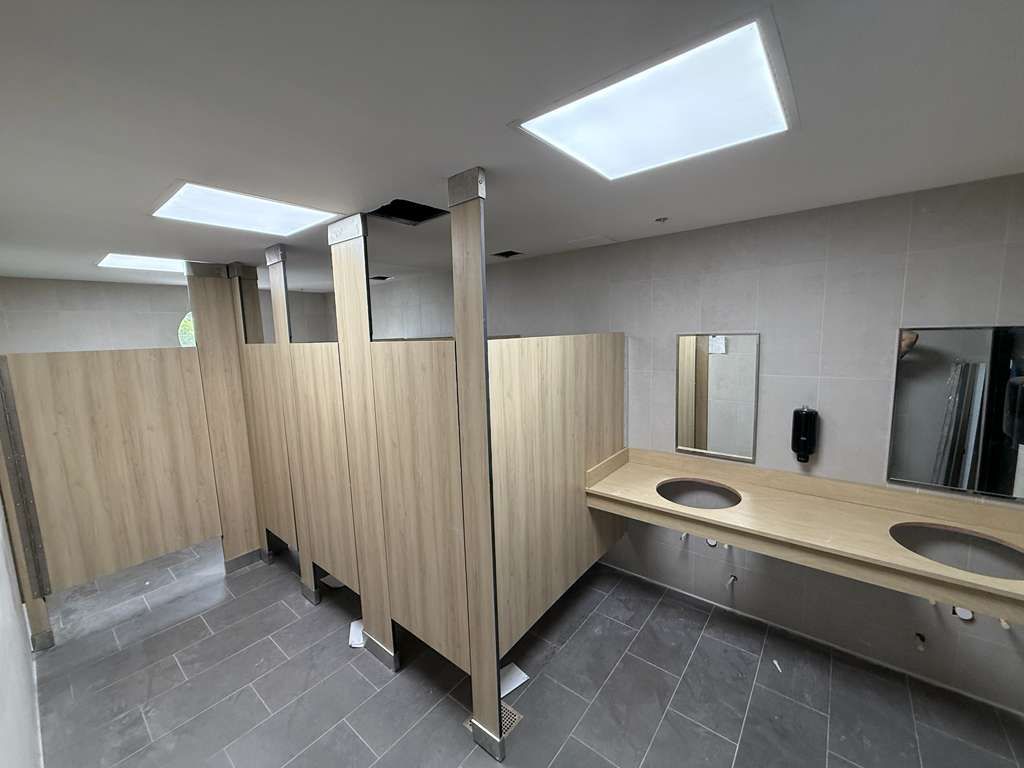 High-durability solid HDPE toilet partition stalls showing custom masonry wall offsets